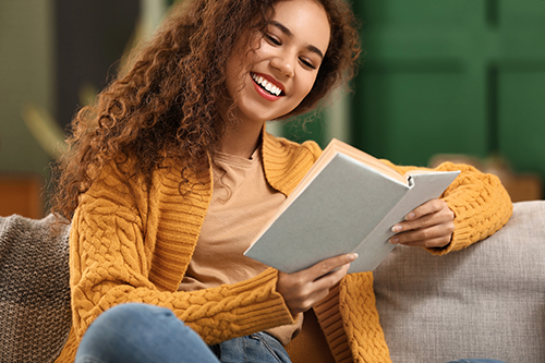 Young African-American woman in yellow cardigan reading book on Young African-American woman in yellow cardigan reading book on
